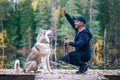 Man with a husky dog Ã¢â¬â¹Ã¢â¬â¹on the pier of a beautiful lake, autumn mood. Young man training a dog in nature